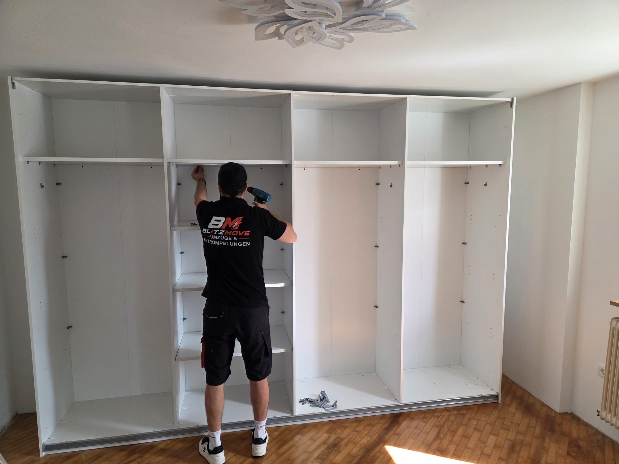 BlitzMove Mitarbeiter bei der Möbelmontage eines großen Kleiderschranks